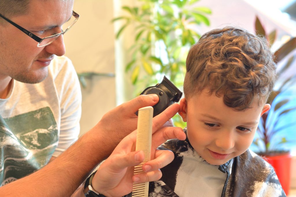 Cute boy getting a haircut at the hairdresser.